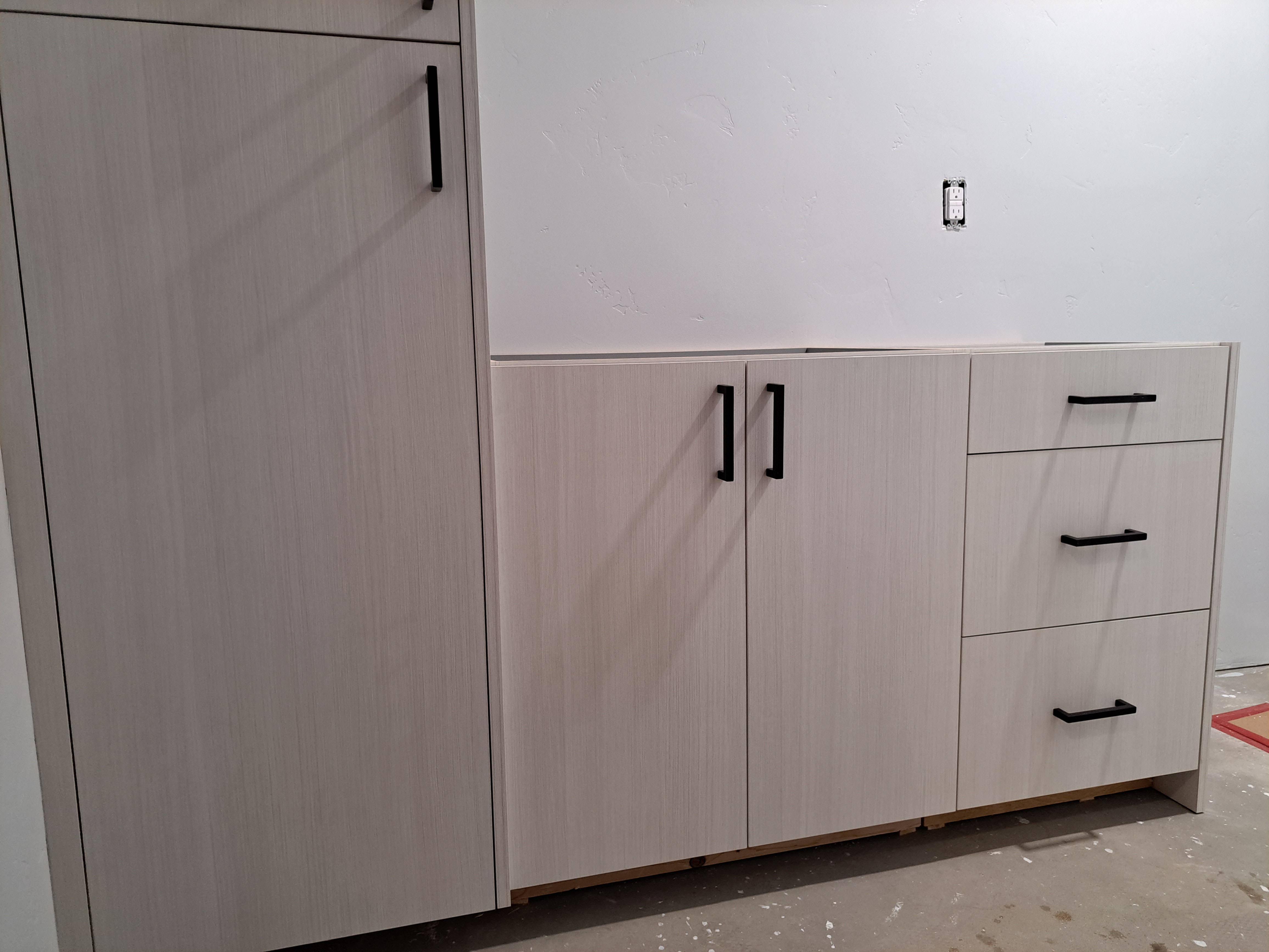 A white cabinet is being installed in a room.