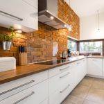 Brick wall in spacious modern designed white kitchen with marble floor